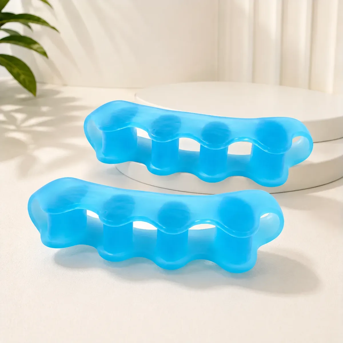 A pair of blue translucent five-toe gel spacers on a cream pedestal