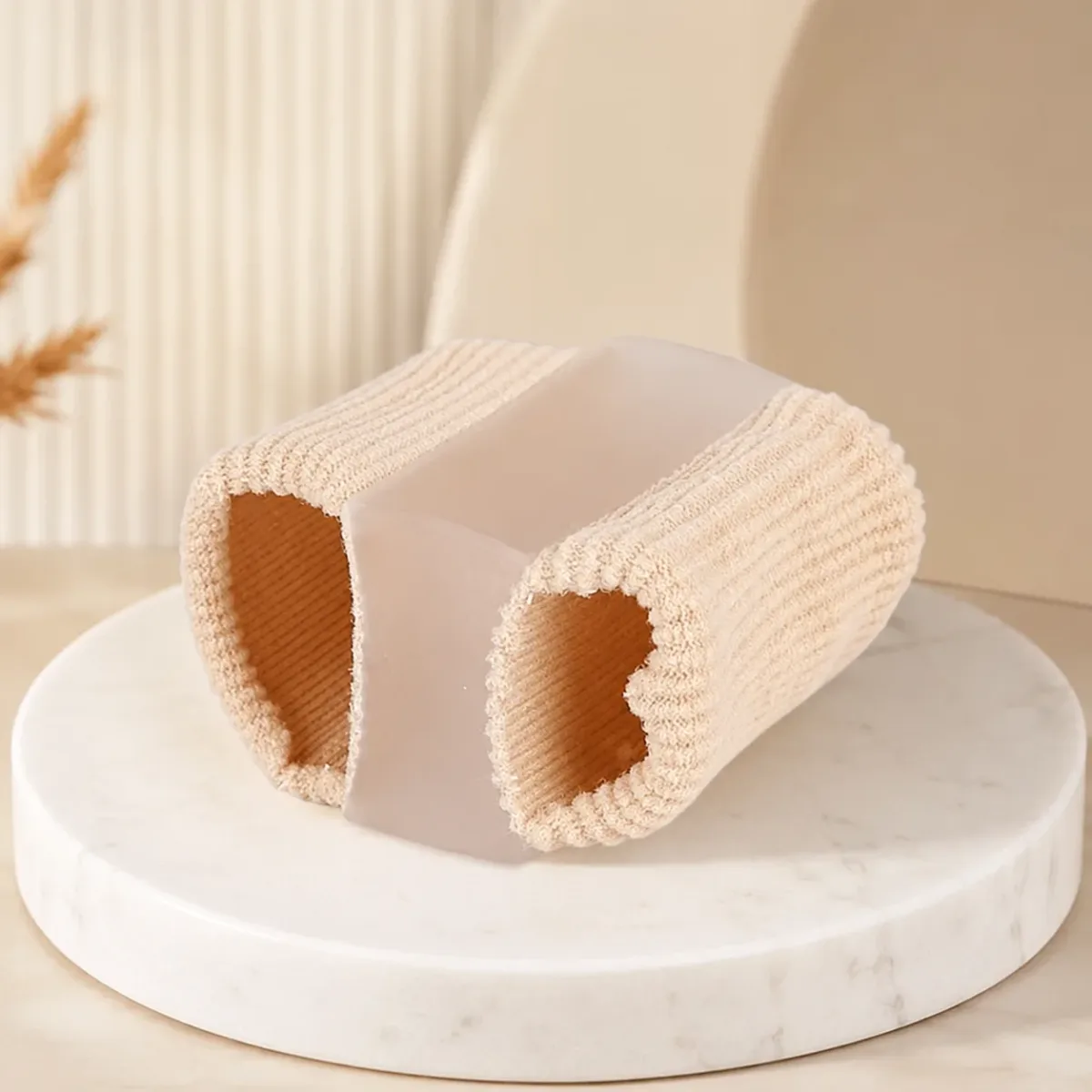 A single beige fabric-covered gel separator tube standing on a pale marble surface